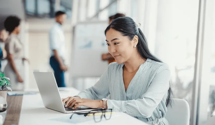 A woman stilling at a desk working on a laptop