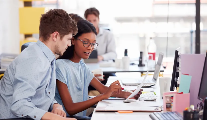 Man and woman discussing work at an office desk